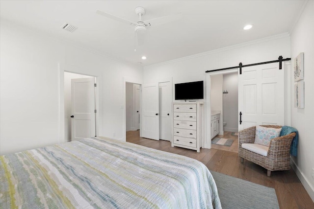 bedroom featuring crown molding, connected bathroom, ceiling fan, hardwood / wood-style flooring, and a barn door