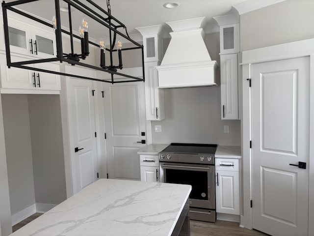 kitchen featuring white cabinetry, custom exhaust hood, a notable chandelier, and electric stove