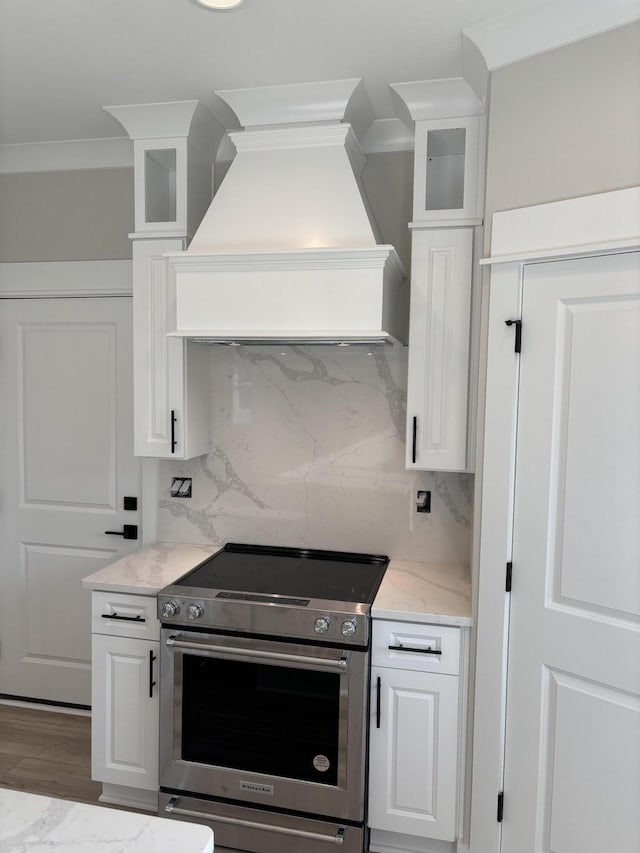 kitchen featuring premium range hood, stainless steel electric range oven, and white cabinetry