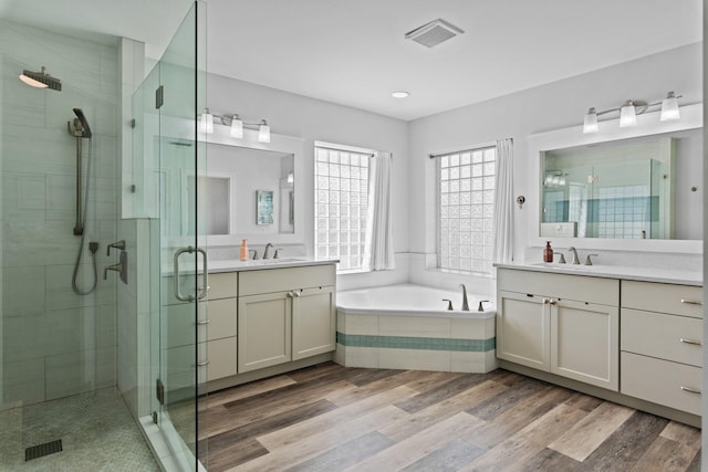 bathroom with independent shower and bath, vanity, and hardwood / wood-style floors