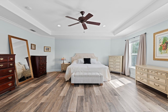 bedroom with a raised ceiling, ornamental molding, hardwood / wood-style flooring, and ceiling fan