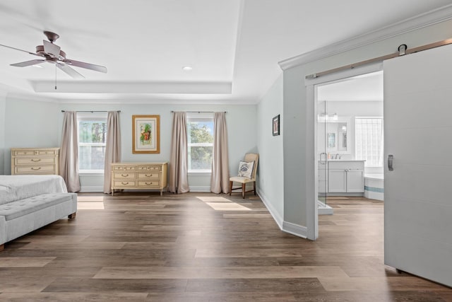 unfurnished room featuring dark wood-type flooring, ornamental molding, a raised ceiling, ceiling fan, and a barn door