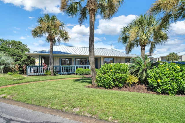 view of front of property featuring a standing seam roof, metal roof, a front lawn, and a porch