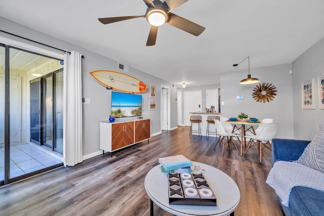 living area with visible vents, ceiling fan, baseboards, and wood finished floors