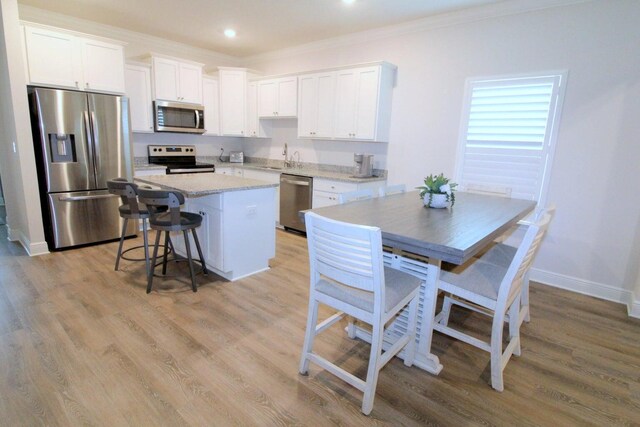 kitchen featuring appliances with stainless steel finishes, a kitchen island, white cabinets, and light hardwood / wood-style floors