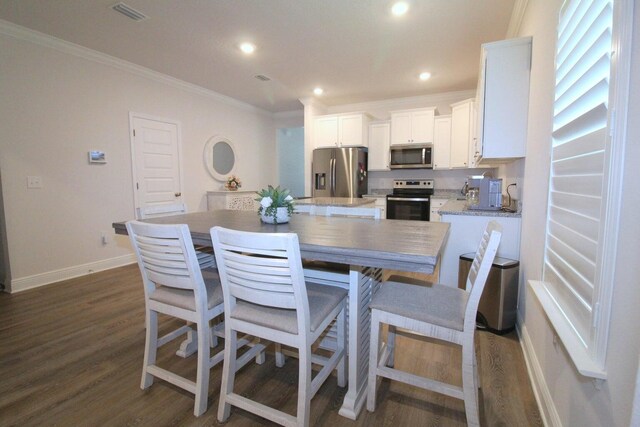 kitchen featuring stainless steel appliances, dark hardwood / wood-style floors, crown molding, and white cabinetry