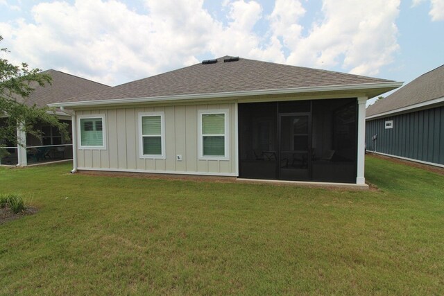 rear view of house featuring a lawn and a sunroom