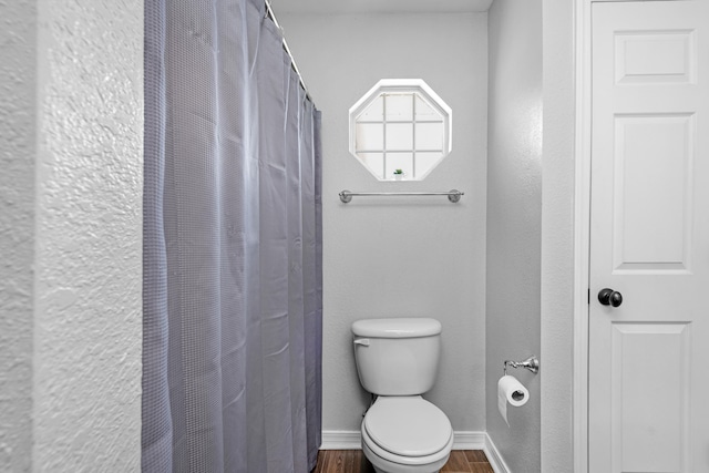 bathroom featuring wood-type flooring, toilet, and a shower with curtain