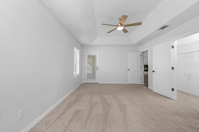 unfurnished room featuring light carpet, a raised ceiling, and ceiling fan