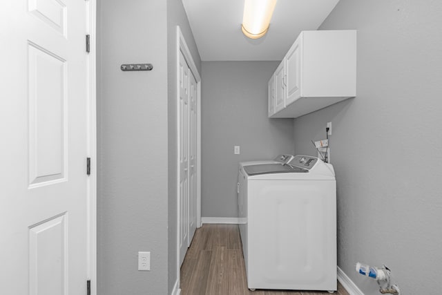 clothes washing area featuring cabinets, washer and dryer, and light hardwood / wood-style floors