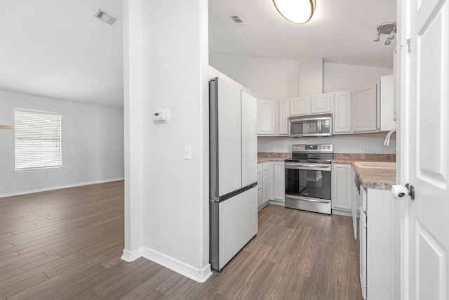 kitchen featuring lofted ceiling, sink, dark hardwood / wood-style floors, white cabinetry, and appliances with stainless steel finishes