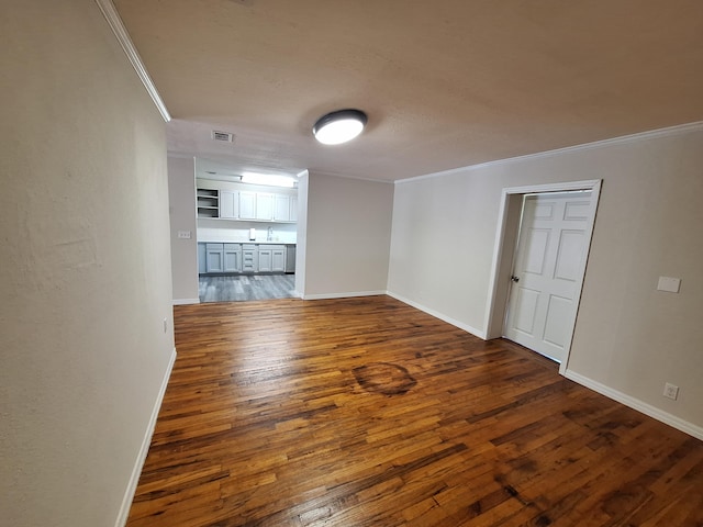 empty room with crown molding, sink, and dark hardwood / wood-style flooring