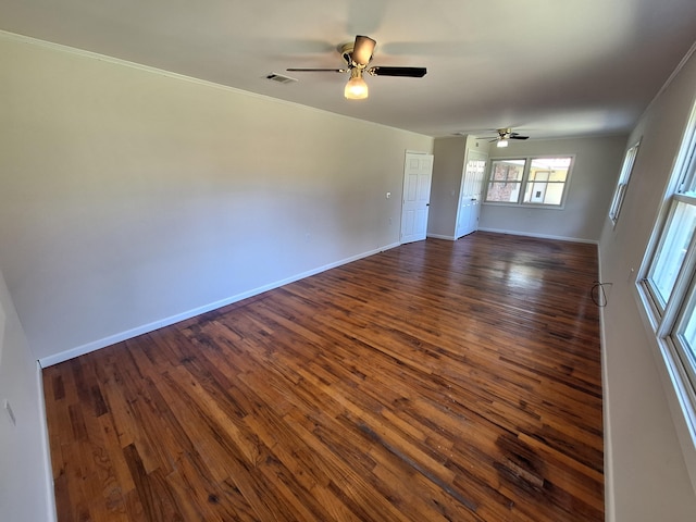 spare room with baseboards, visible vents, dark wood-type flooring, and a ceiling fan