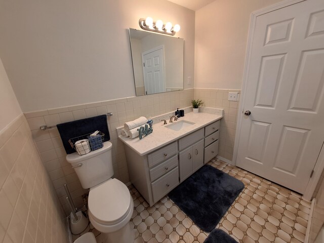 bathroom with vanity, toilet, tile walls, and tasteful backsplash