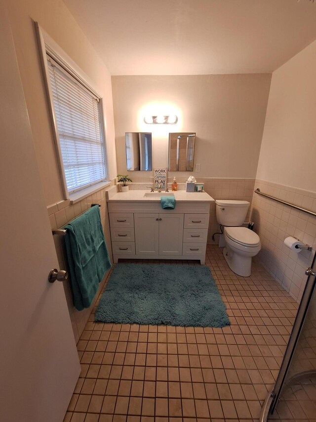 bathroom with tile patterned flooring, vanity, toilet, and tile walls