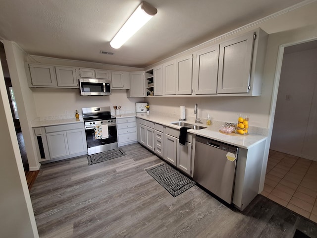 kitchen featuring a textured ceiling, sink, appliances with stainless steel finishes, and light hardwood / wood-style floors