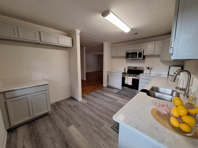 kitchen featuring gray cabinetry, wood-type flooring, stainless steel appliances, and sink