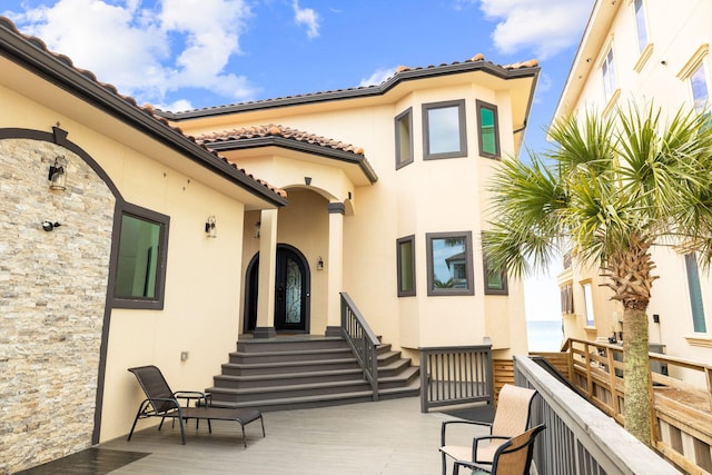 back of property with stucco siding and a tiled roof