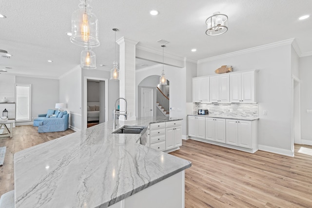 3478 Scenic Highway 98, Destin, FL 32541 - kitchen with light wood finished floors, white cabinets, arched walkways, a sink, and decorative backsplash