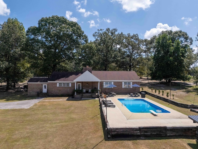 pool with a diving board, a lawn, a patio area, and fence