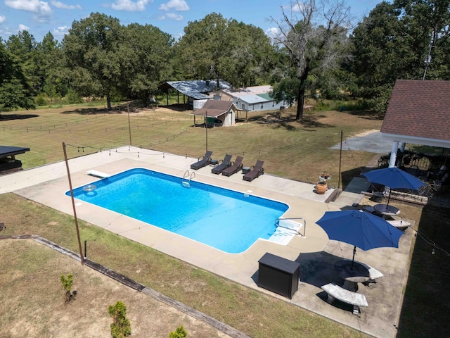 outdoor pool with a diving board, a lawn, and a patio