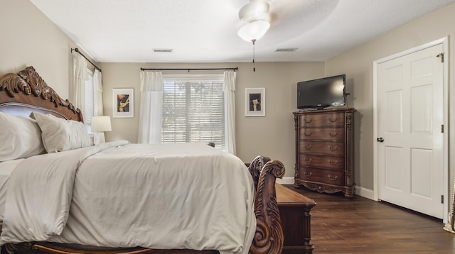 bedroom with dark wood-style floors, baseboards, visible vents, and a ceiling fan