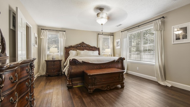 bedroom featuring a textured ceiling, a ceiling fan, visible vents, baseboards, and dark wood finished floors