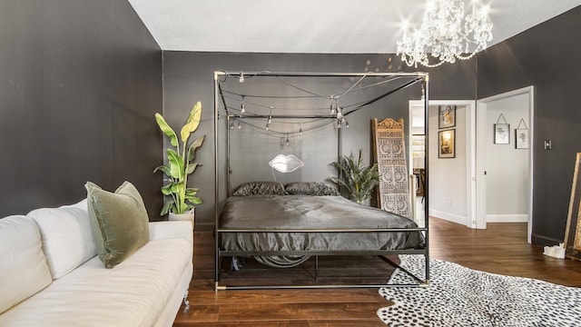 bedroom featuring a chandelier, wood finished floors, and baseboards