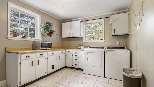 laundry area featuring light tile patterned floors, ornamental molding, washing machine and dryer, and cabinet space