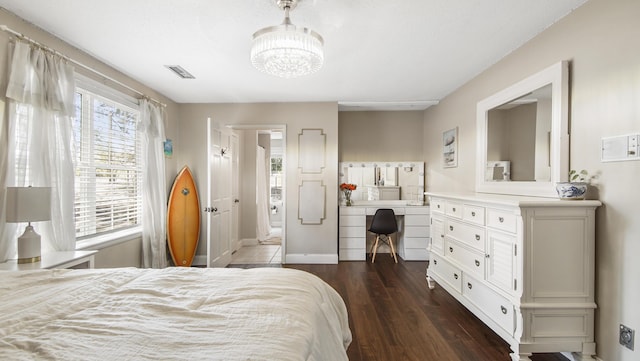 bedroom with dark wood-style flooring, visible vents, and an inviting chandelier