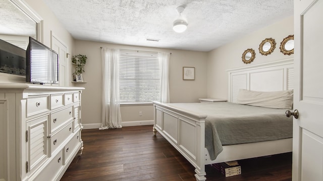 bedroom featuring a textured ceiling, dark wood-style flooring, visible vents, and baseboards