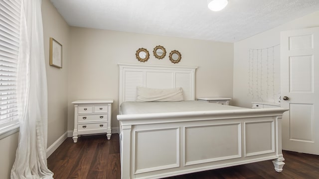 bedroom featuring a textured ceiling, dark wood-type flooring, and baseboards