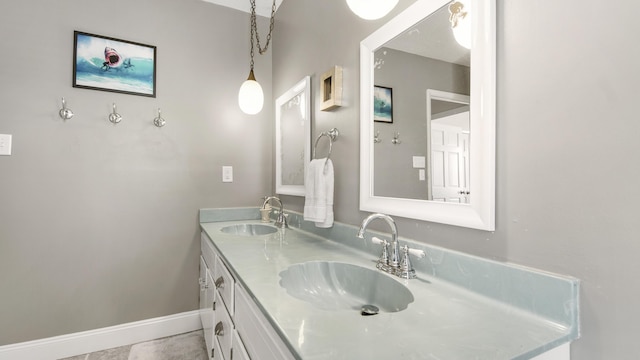 bathroom with double vanity, a sink, and baseboards