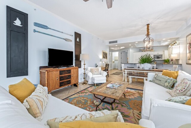 tiled living room featuring ceiling fan with notable chandelier and ornamental molding