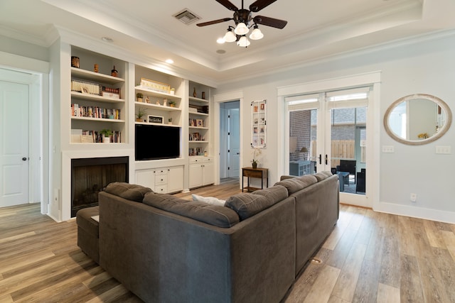 living room featuring crown molding, a tray ceiling, light hardwood / wood-style flooring, and ceiling fan