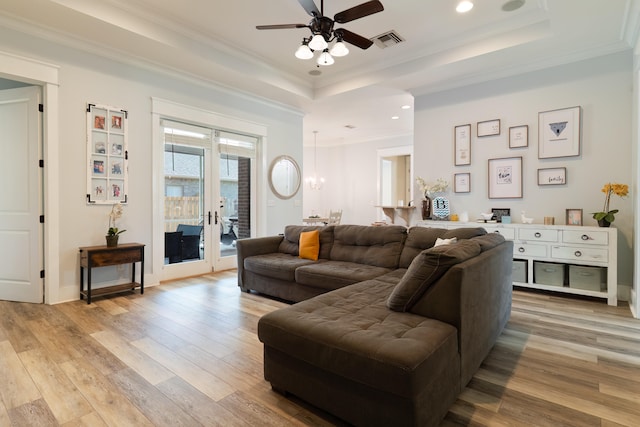 living room with crown molding, light hardwood / wood-style flooring, a tray ceiling, and ceiling fan