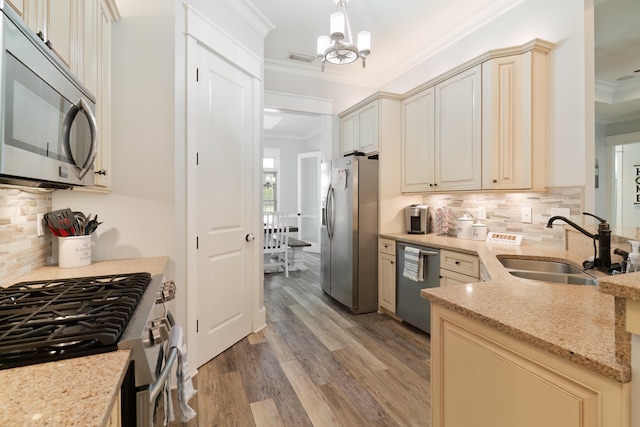 kitchen with stainless steel appliances, cream cabinets, light hardwood / wood-style flooring, and hanging light fixtures