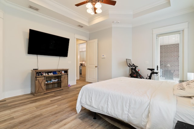 bedroom featuring crown molding, a tray ceiling, light wood-type flooring, and ceiling fan