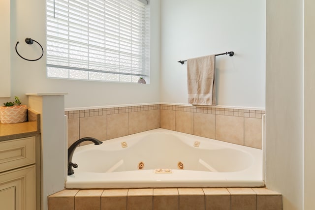 bathroom with vanity and tiled tub