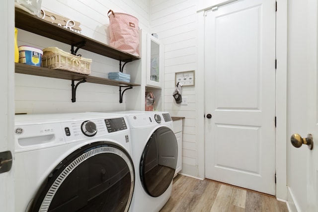 washroom with washer and dryer, wooden walls, and light wood-type flooring