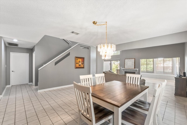 tiled dining space featuring a chandelier and a textured ceiling