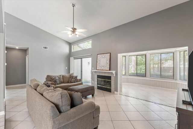 tiled living room featuring a wealth of natural light, high vaulted ceiling, ceiling fan, and a tile fireplace