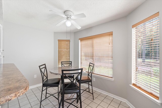 tiled dining area with ceiling fan, plenty of natural light, and a textured ceiling