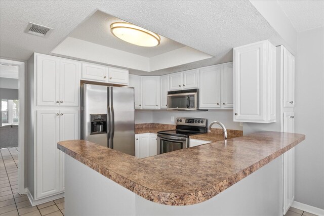 kitchen featuring a textured ceiling, kitchen peninsula, appliances with stainless steel finishes, and light tile patterned flooring