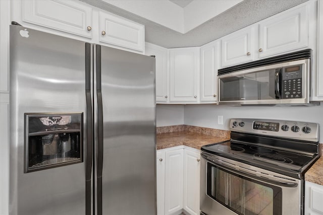 kitchen with a textured ceiling, stainless steel appliances, and white cabinets