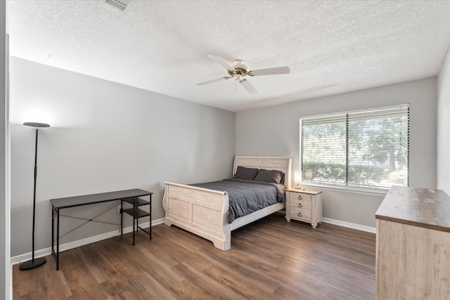 bedroom with a textured ceiling, ceiling fan, and dark hardwood / wood-style floors