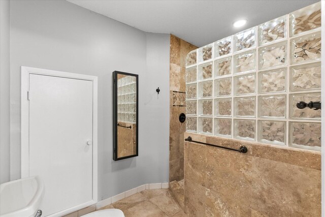 bathroom with toilet, a tile shower, and tile patterned floors