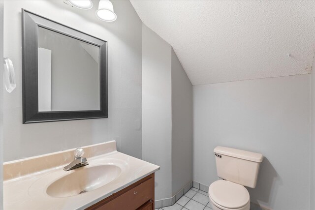 bathroom featuring tile patterned floors, vaulted ceiling, toilet, vanity, and a textured ceiling