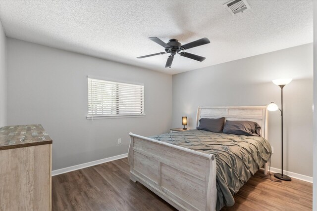 bedroom with ceiling fan, dark hardwood / wood-style floors, and a textured ceiling