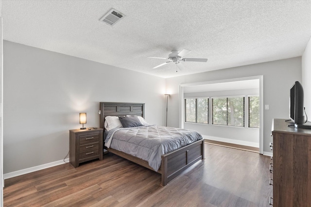 bedroom with a textured ceiling, ceiling fan, and dark hardwood / wood-style floors